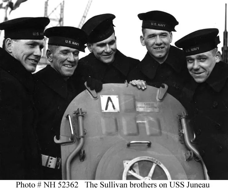 The five Sullivan brothers in Navy peacoats grouped around a hatch aboard USS Juneau on 14 February 1942