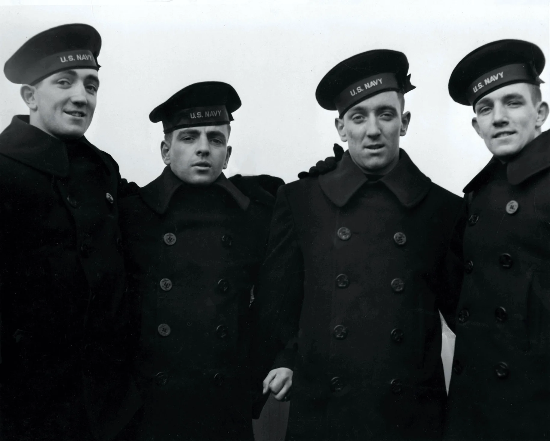 Four Rogers brothers in U.S. Navy peacoats and flat caps posing together at the commissioning of USS Juneau in February 1942